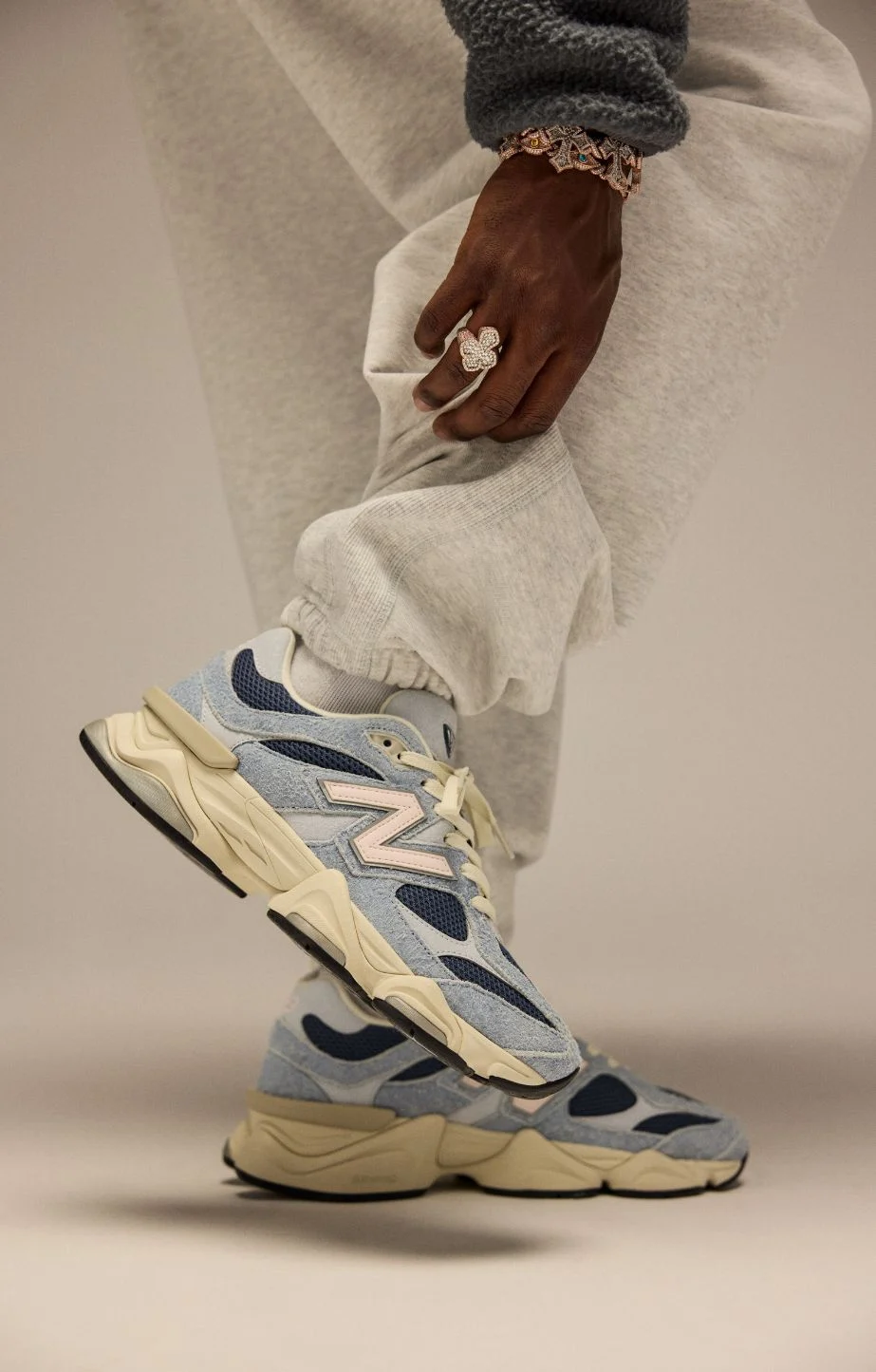 A knee down image of a person against a beige background. 